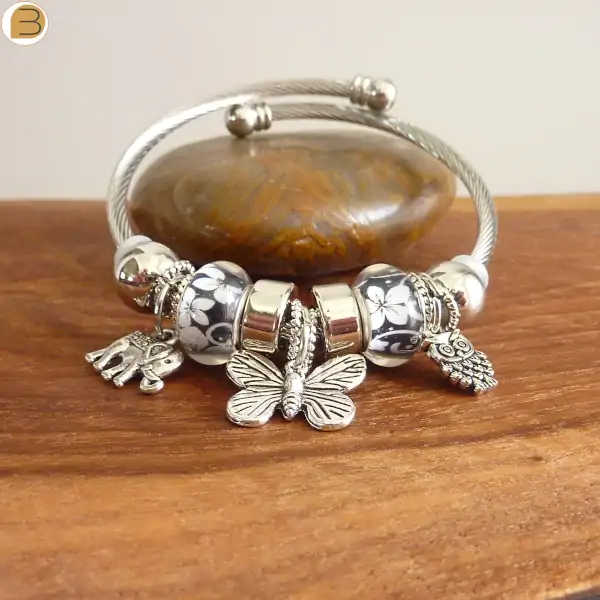Bracelet acier avec breloques argentées éléphant chouette et papillon, perles noires et blanches
