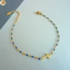 Bracelet en acier inoxydable doré pour femme avec ses fines perles bleu marine et son pendentif croix chrétienne