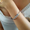 Bracelet en acier pour femme à ouverture charnière et clips de fermeture orné de zircons blancs