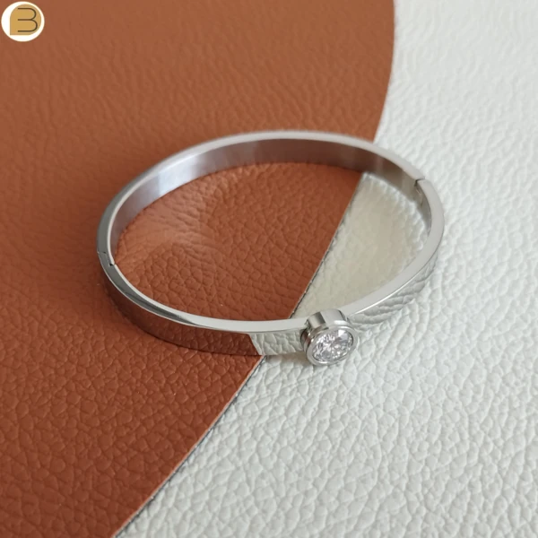 Bracelet en acier inoxydable pour femme à ouverture charnière, couleur argent, orné d'un zircon blanc.