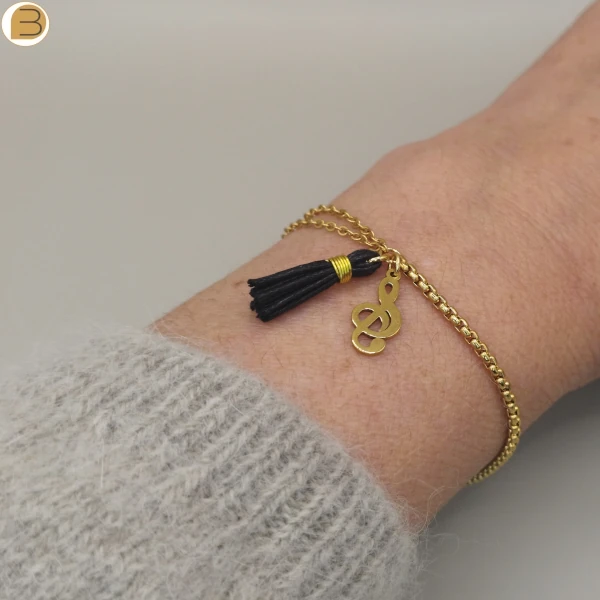 Bracelet fait main en France pour femme en acier inoxydable doré, chaîne asymétrique, pendentifs pompon et note de musique.