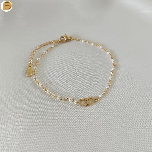 Bracelet en acier inoxydable doré pour femme avec ses fines perles blanches et son pendentif cœur