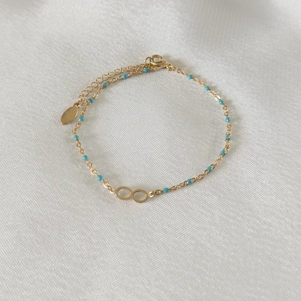 Bracelet en acier inoxydable doré pour femme avec ses fines perles turquoise et son pendentif infini.