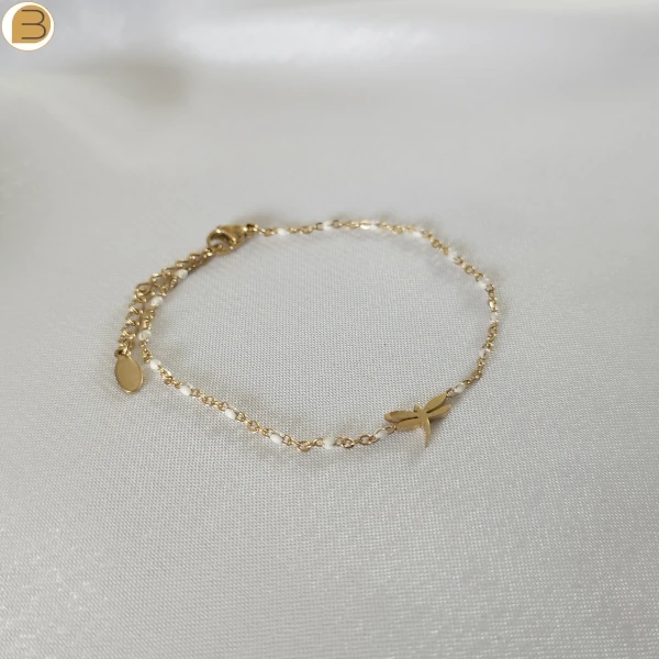 Bracelet en acier inoxydable doré pour femme avec ses fines perles blanches et son pendentif libellule.