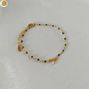 Bracelet en acier inoxydable doré pour femme avec ses fines perles noires et son pendentif libellule.