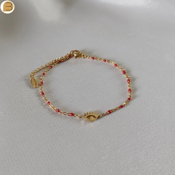 Bracelet en acier inoxydable doré pour femme avec ses fines perles rouges et son pendentif mauvais œil.